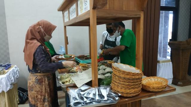 Potret seorang pedagang berjualan makanan dengan angkringan kayu bewarna cokelat.