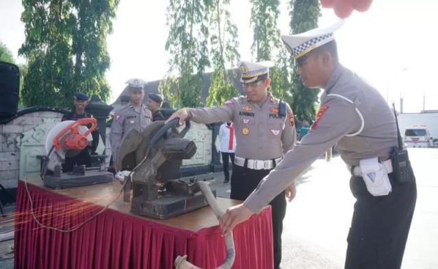 Petugas saat memusnahkan ratusan knalpot brong dengan cara dipotong menggunakan gerinda, di kompleks alun-alun Cilacap