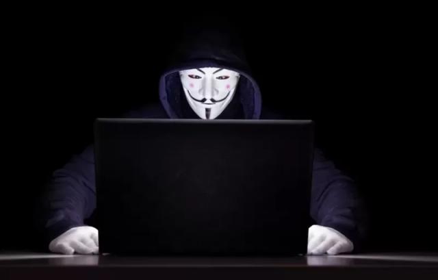 Gambar seseorang yang mengenakan topeng Vendetta di depan laptop