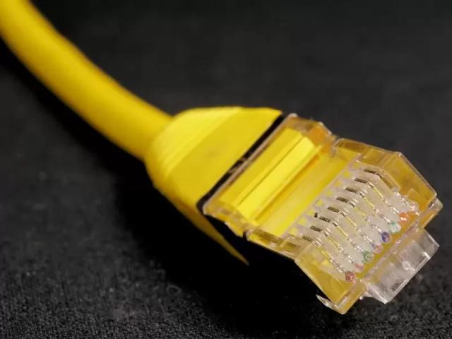 Gambar sebuah kabel ethernet berwarna kuning yang tergeletak.