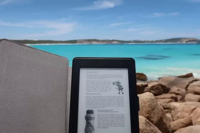 Gambar sebuah tablet berwarna dihitam yang sedang dipakai di pinggir laut.