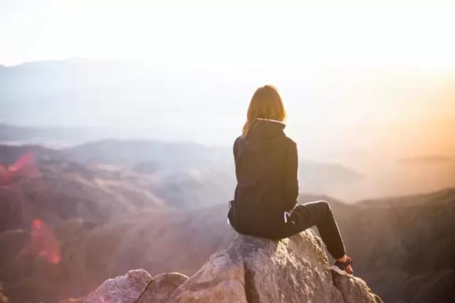 Seorang yang sedang duduk di bukit tanpa membawa perlengkapan traveling wanita.