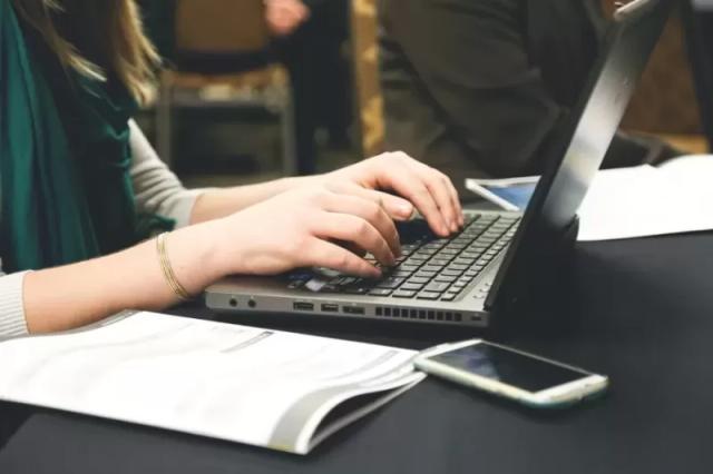 Gambar tangan dari seseorang yang sedang mengoperasikan laptop berwarna hitam.