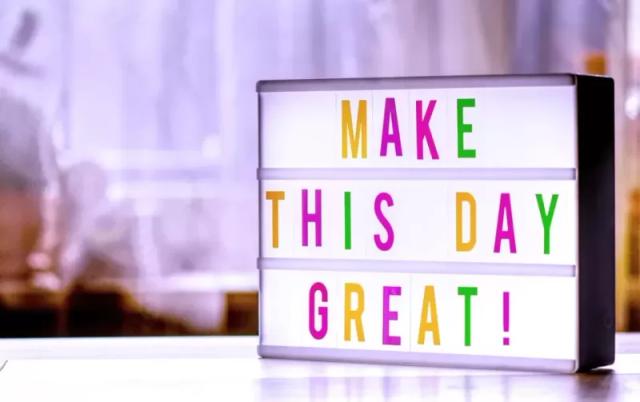 Gambar sebuah papan bertuliskan 'Make This Day Great!' yang berwarna-warni.