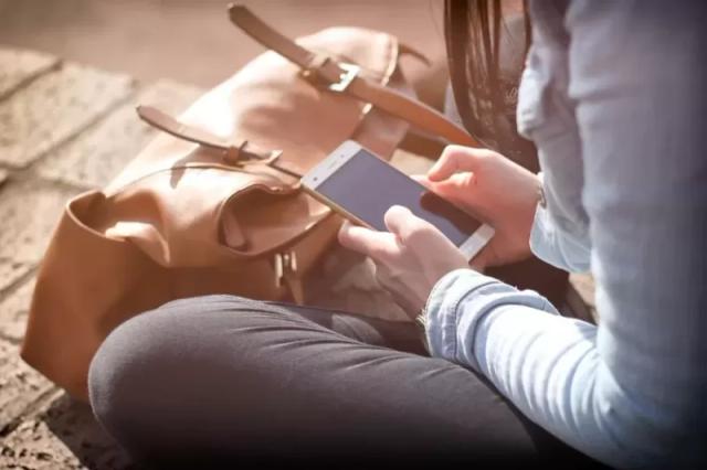 Gambar seorang wanita sedang menggunakan ponselnya.