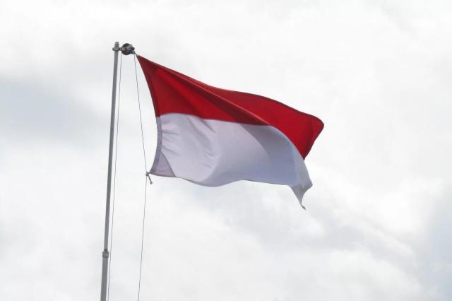 Gambar bendera merah putih Indonesia yang berkibar dan terpasang di tiang.