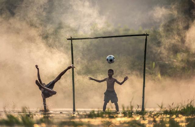 Dua orang anak kecil yang sedang bermain sepak bola, ilustrasi olahraga menurunkan berat badan untuk anak.