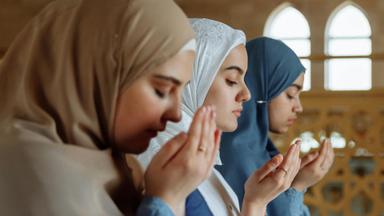 Potret tiga perempuan berhijab yang sedang berdoa.