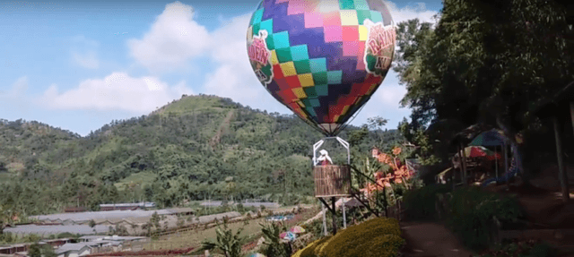 Gambar sebuah balon udara berwarna-warni di taman.