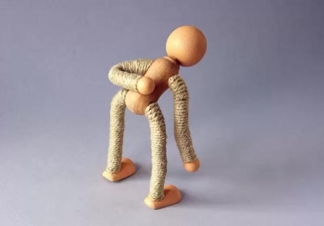 Gambar sebuah boneka kayu berwarna cokelat yang sedang memegang punggungnya, ilustrasi cara mengatasi badan sakit semua.