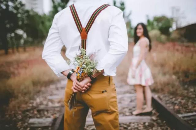 Gambar seorang pria sedang menyembunyikan bunga yang ingin ia berikan kepada pasangannya.