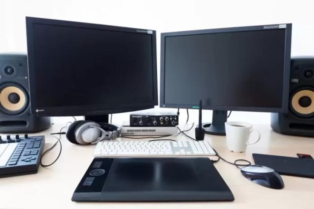 Gambar dua buah monitor berwarna hitam lengkap dengan Keyboard, Mouse dan Speaker.