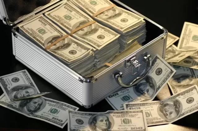 Gambar segepok uang dolar di dalam sebuah koper berwarna putih.