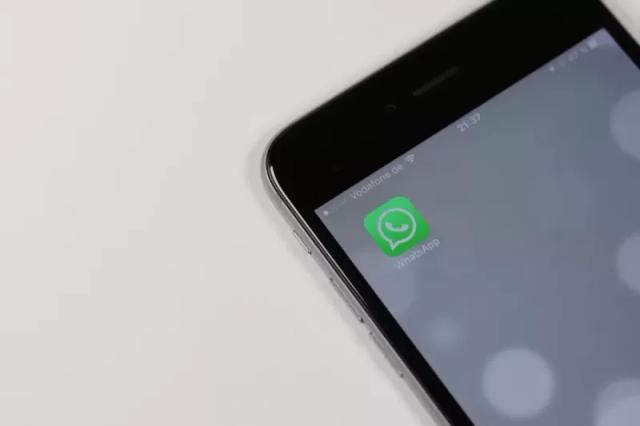 Gambar sebuah smartphone menyala yang berisi aplikasi WhatsApp berwarna hijau.