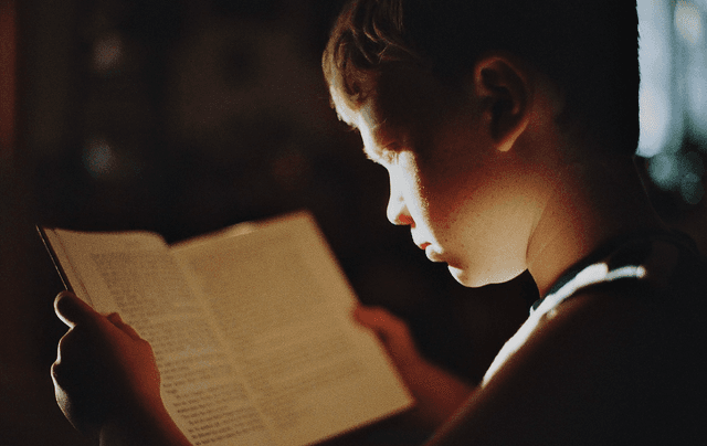 Potret seorang anak sedang membaca buku.