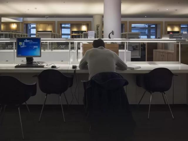 Gambar seorang pria tengah duduk dan bekerja.