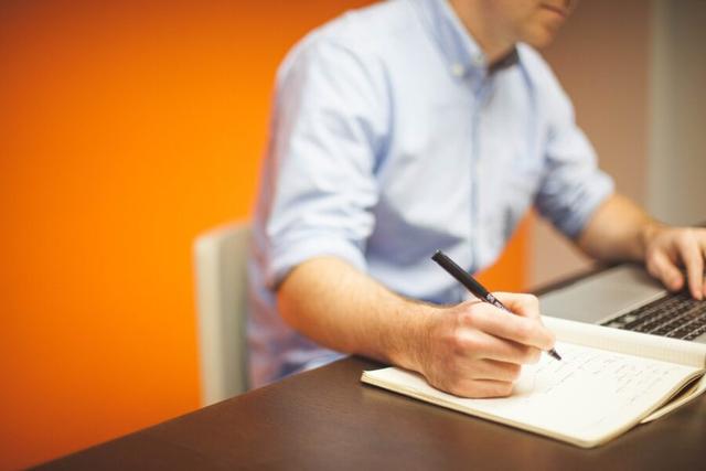 Gambar seseorang yang sedang menuliskan sesuatu di sebuah buku catatan kerja, ilustrasi cara agar cekatan dalam bekerja.