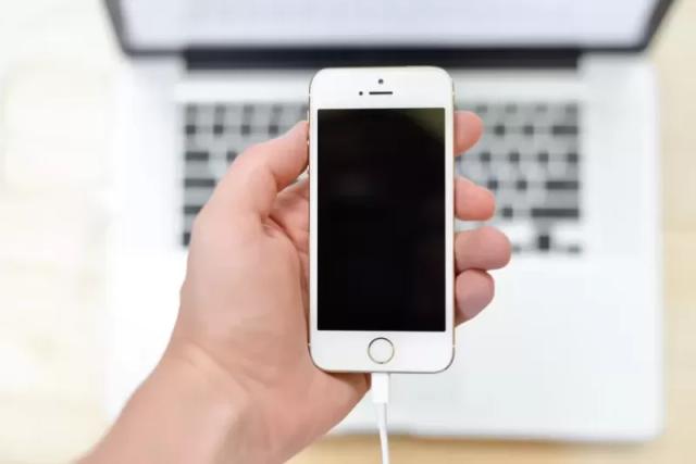 Gambar sebuah smartphont bewarna putih yang sedang digenggam menggunakan satu tangan.