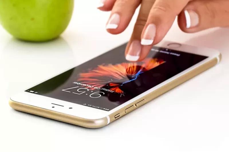 Gambar tangan seseorang sedang menyentuh smartphone iPhone.