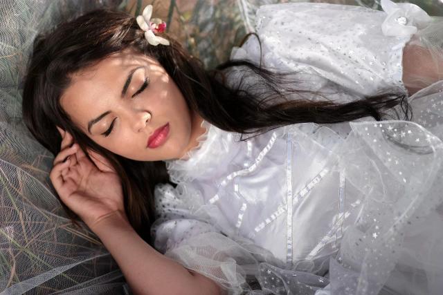 Potret seorang wanita dengan baju putih yang sedang tertidur pulas, ilustrasi cara menghilangkan rasa malas yang berlebihan.