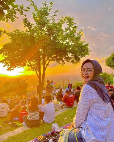 Gambar seorang wanita yang sedang menikmati Sunset, foto ilustrasi spot Sunset di Jogja.