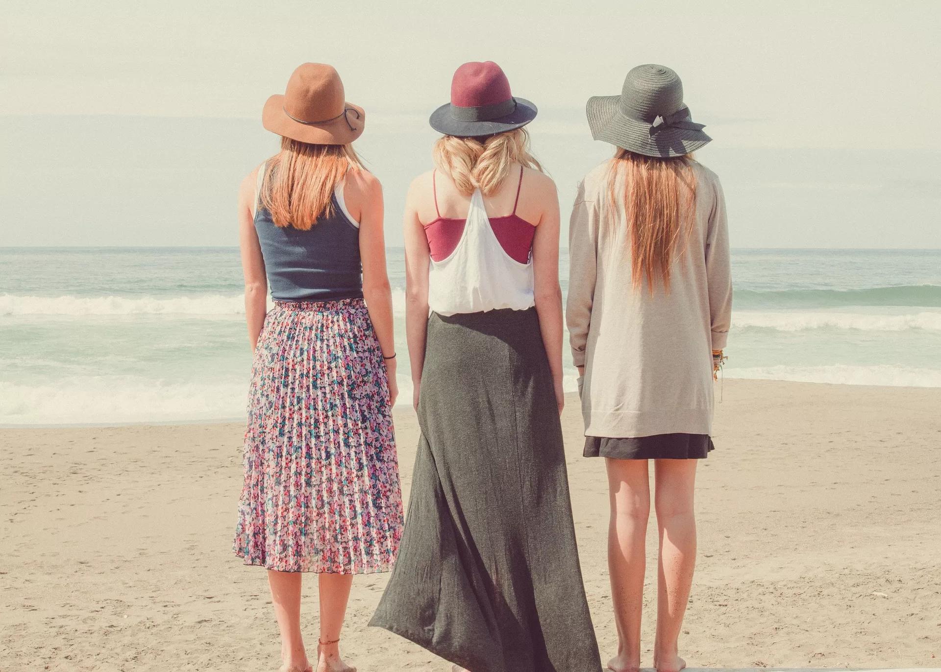 Potret tiga orang wanita yang sedang berdiri tegap di sebuah pantai, ilustrasi cara memperbaiki postur tubuh bungkuk.