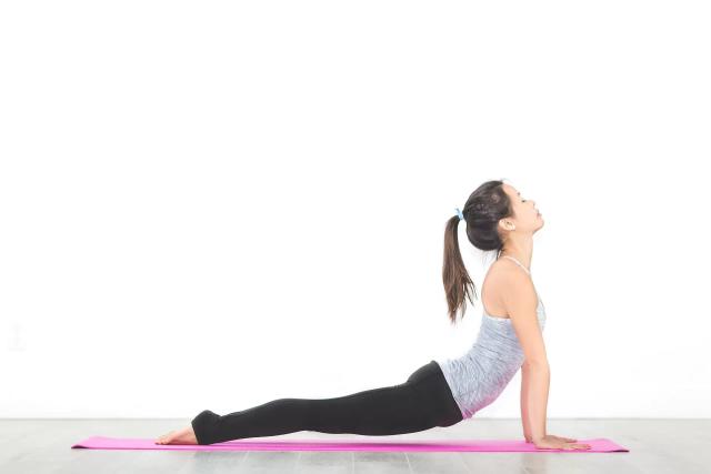 Potret seorang wanita yang sedang melakukan gerakan Yoga, ilustrasi salah satu olahraga untuk memperbaiki postur tubuh yang bungkuk.