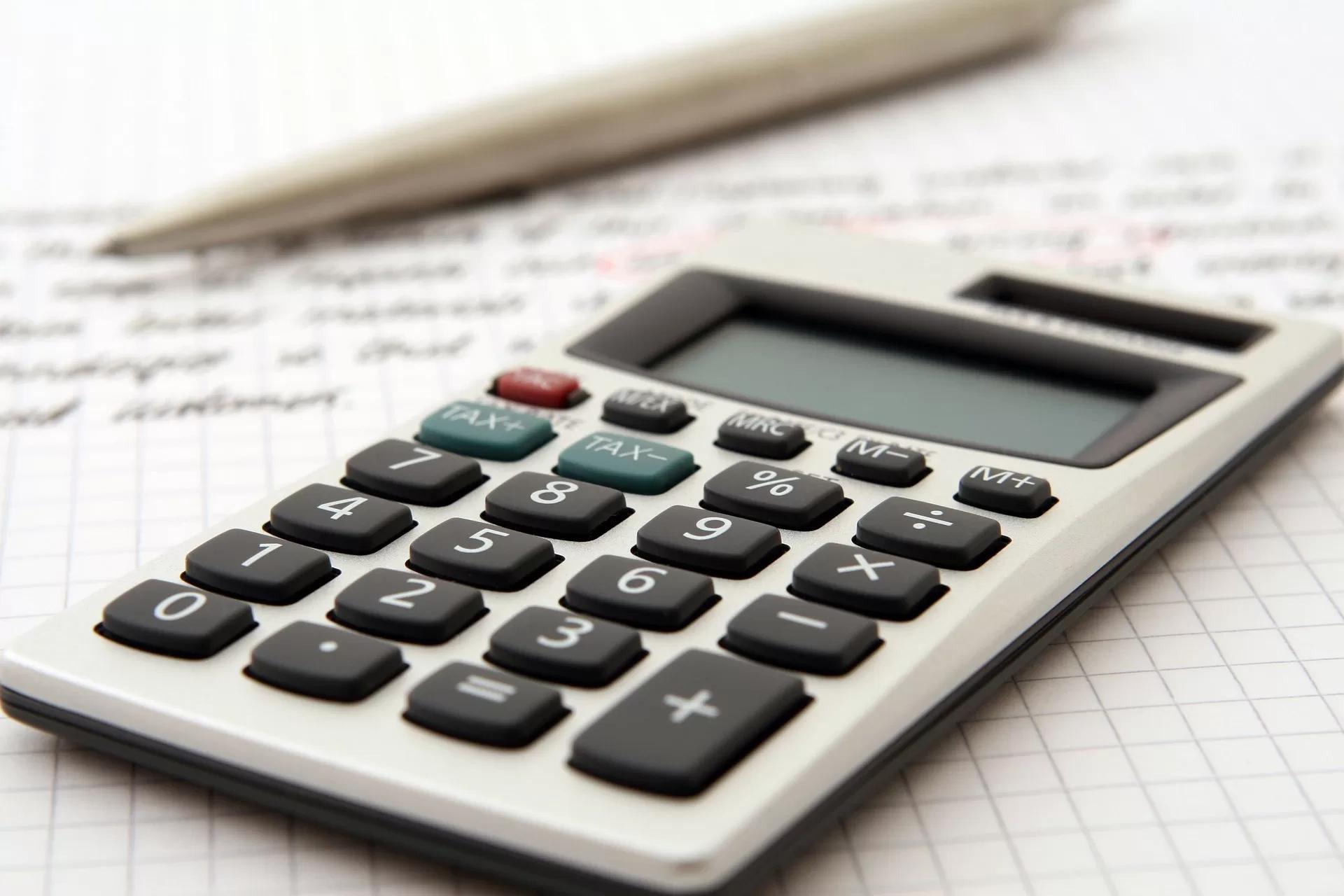 Gambar sebuah kalkulator di atas lembar catatan, ilustrasi tips bebas utang pinjol