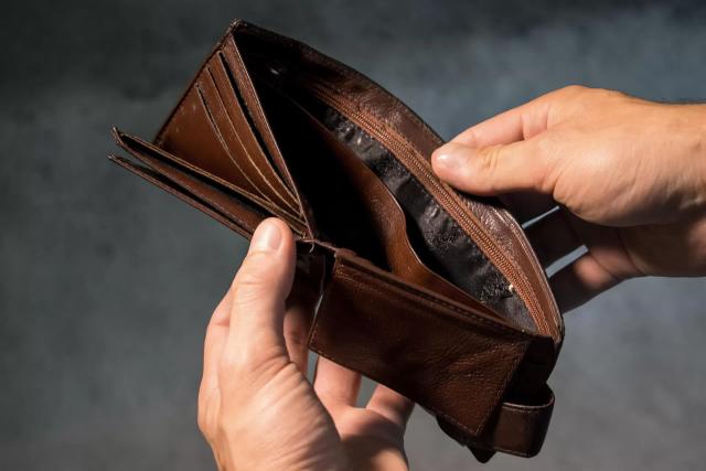 Gambar seseorang yang sedang membuka dompet kosongnya, ilustrasi cara mengatur keuangan untuk belanja di awal bulan.