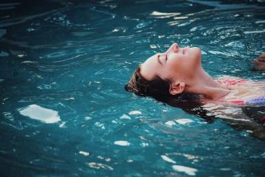 Gambar seorang wanita yang sedang berenang, ilustrasi manfaat mandi setelah olahraga.
